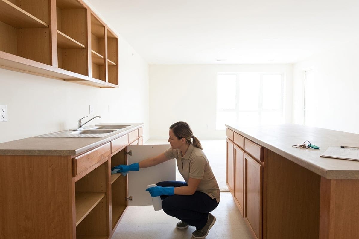 Nettoyage de l'intérieur des placards d'une cuisine dans un logement vide